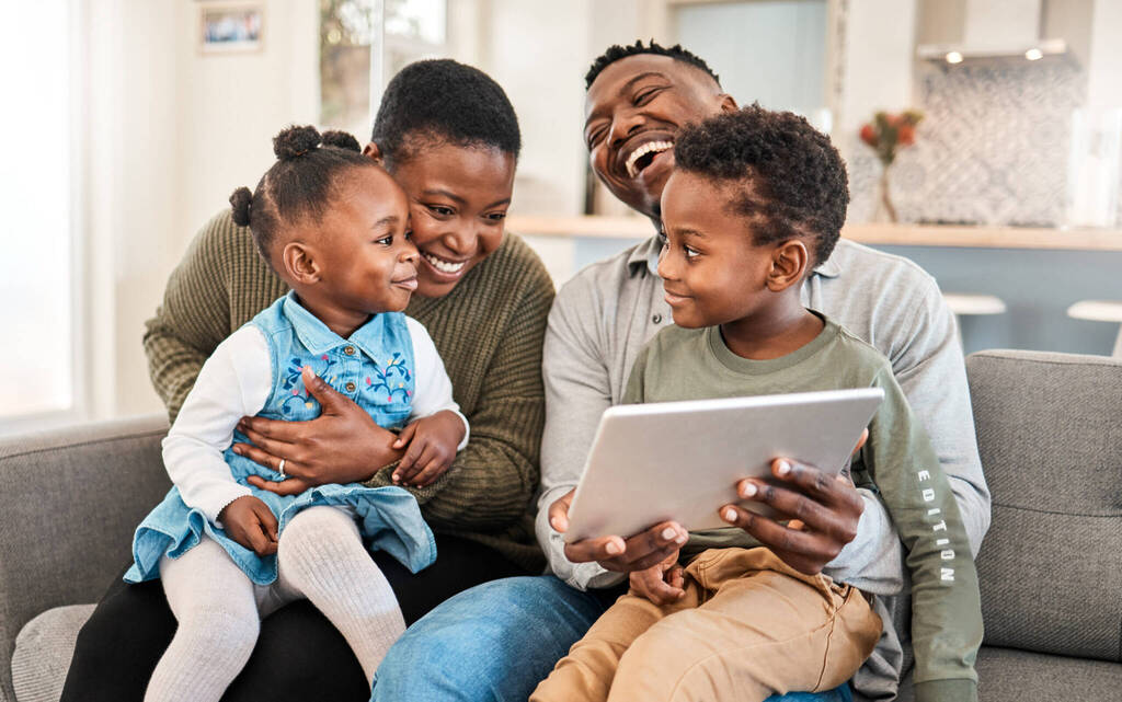 Family Friendly Movies Make The Best Childhood Memories. Shot Of A Happy Young Family Using A Digital Tablet On The Sofa At Home.