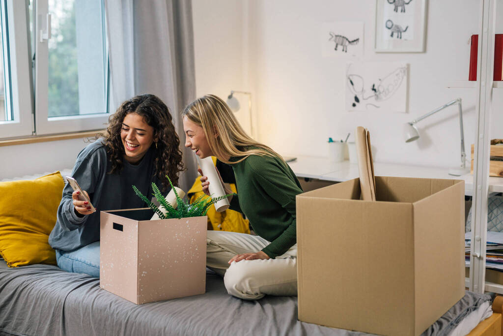 College Female Teenagers Sits On Bed And Using Mobile Phone Dorm