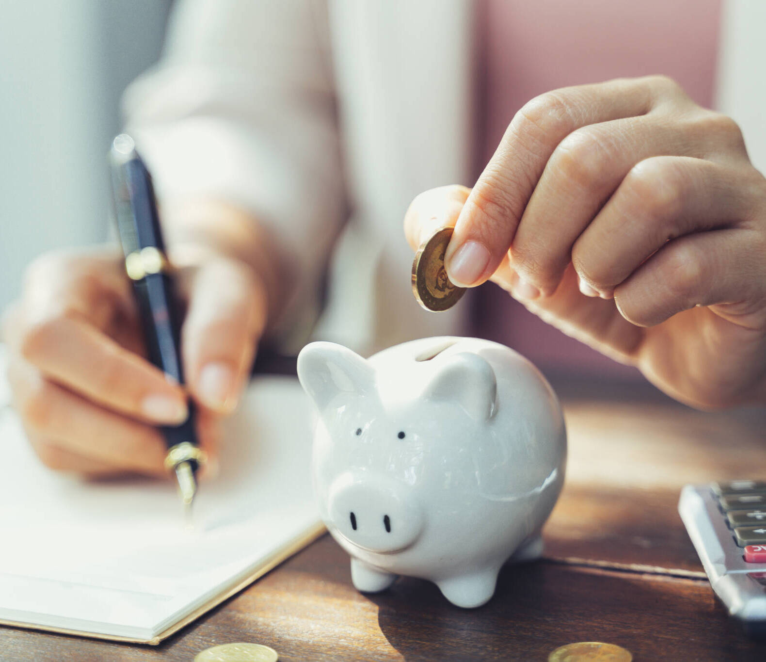 Closeup Of Business Woman Hand Putting Money Coin Into Piggy Bank For Saving Money. Saving Money And Financial Concept Closeup Of Business Woman Hand Putting Money Coin Into Piggy Bank For Saving Money. Saving Money And Financial Concept