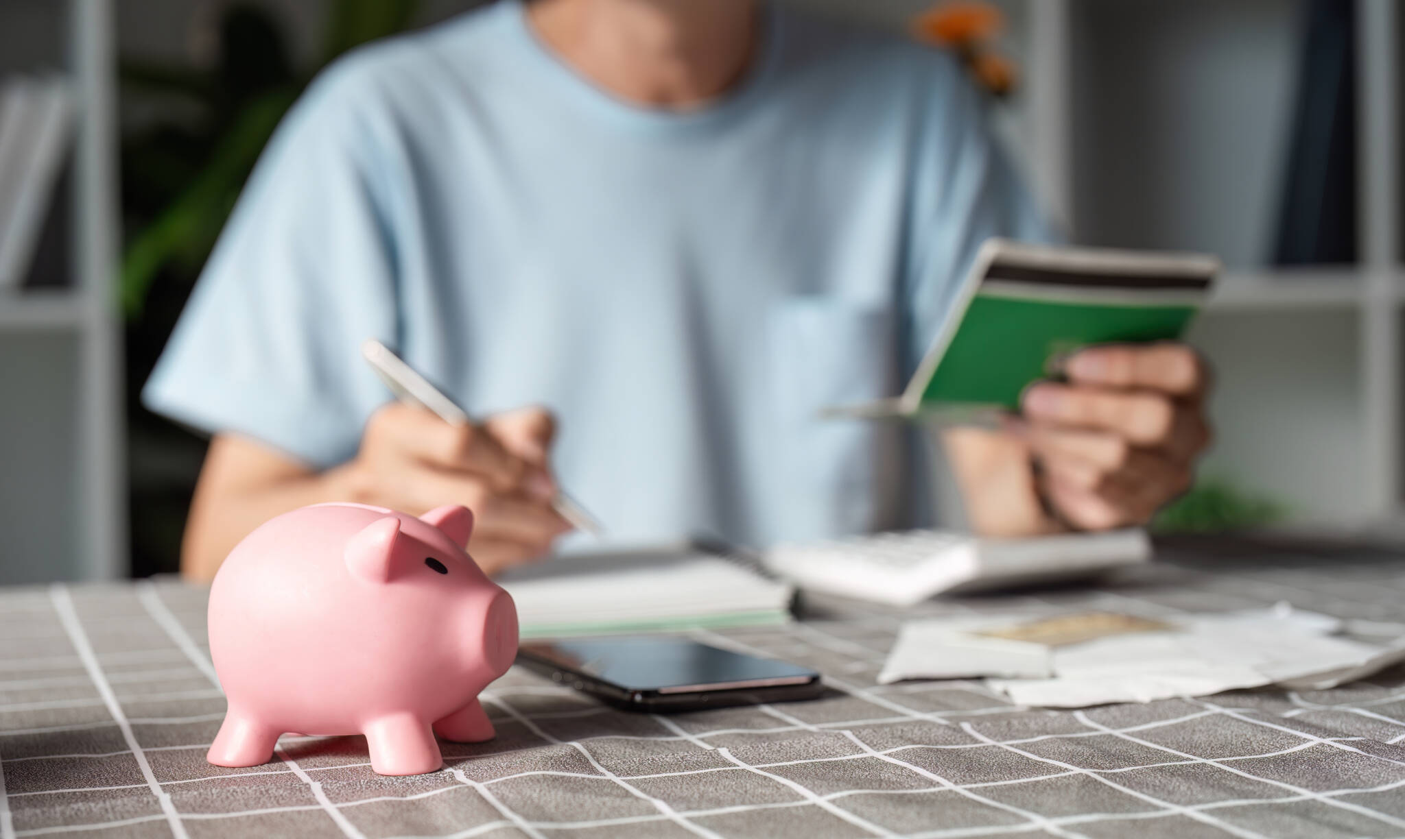 Man Managing Finances And Savings, Focusing On A Pink Piggy Bank While Reviewing Budget Notes And Financial Records